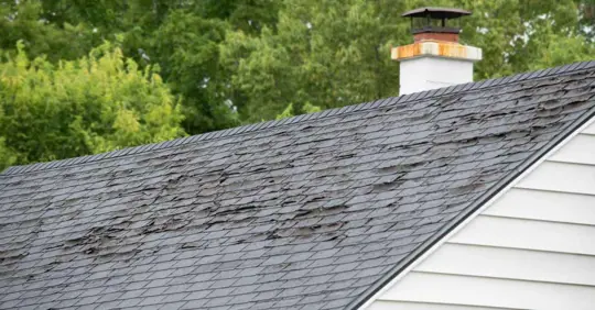 Damaged and old roofing shingles and gutter system on a house